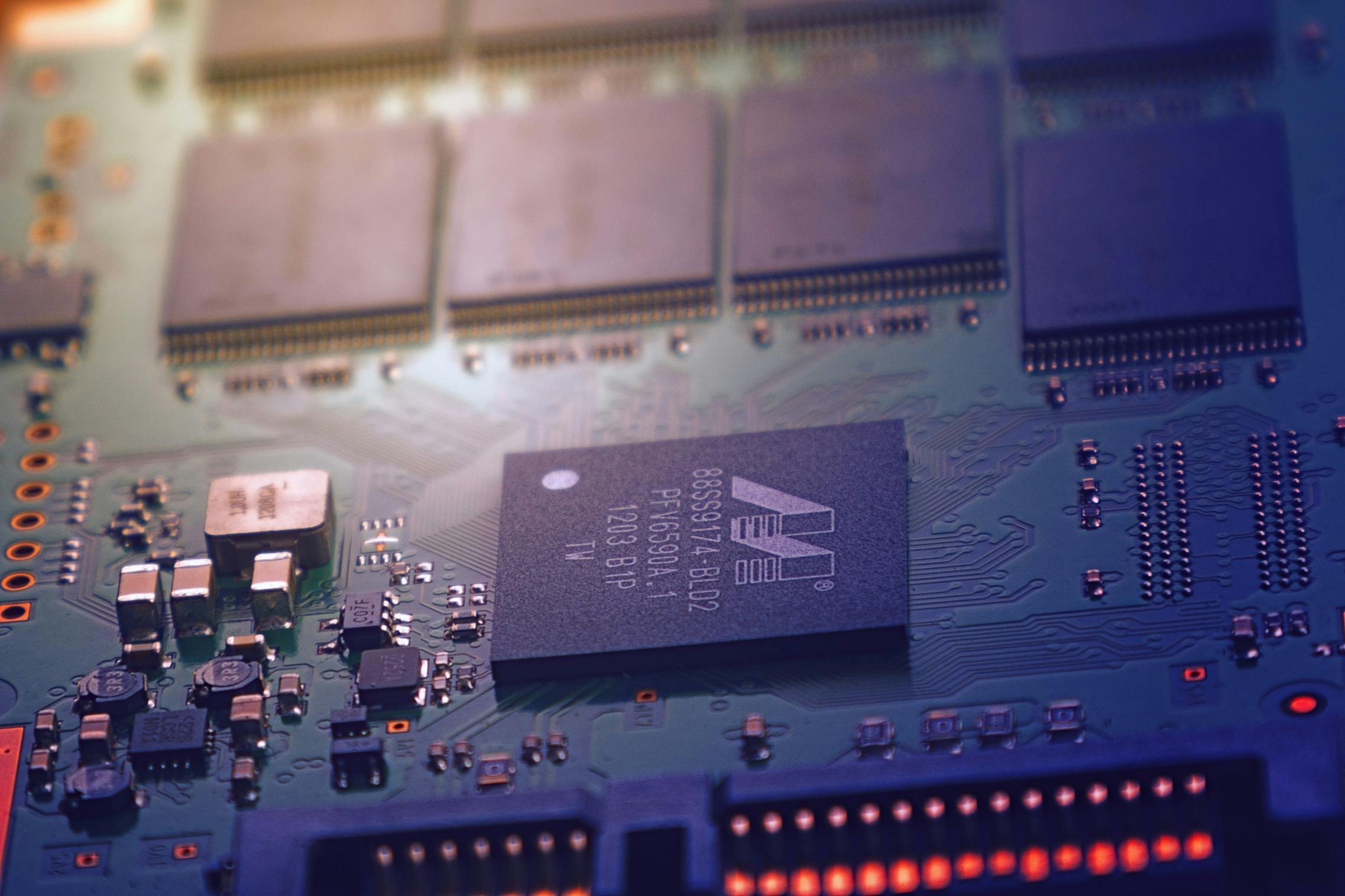 Detailed image of an electronic circuit board showing microchips and intricate wiring in a modern technological setting.