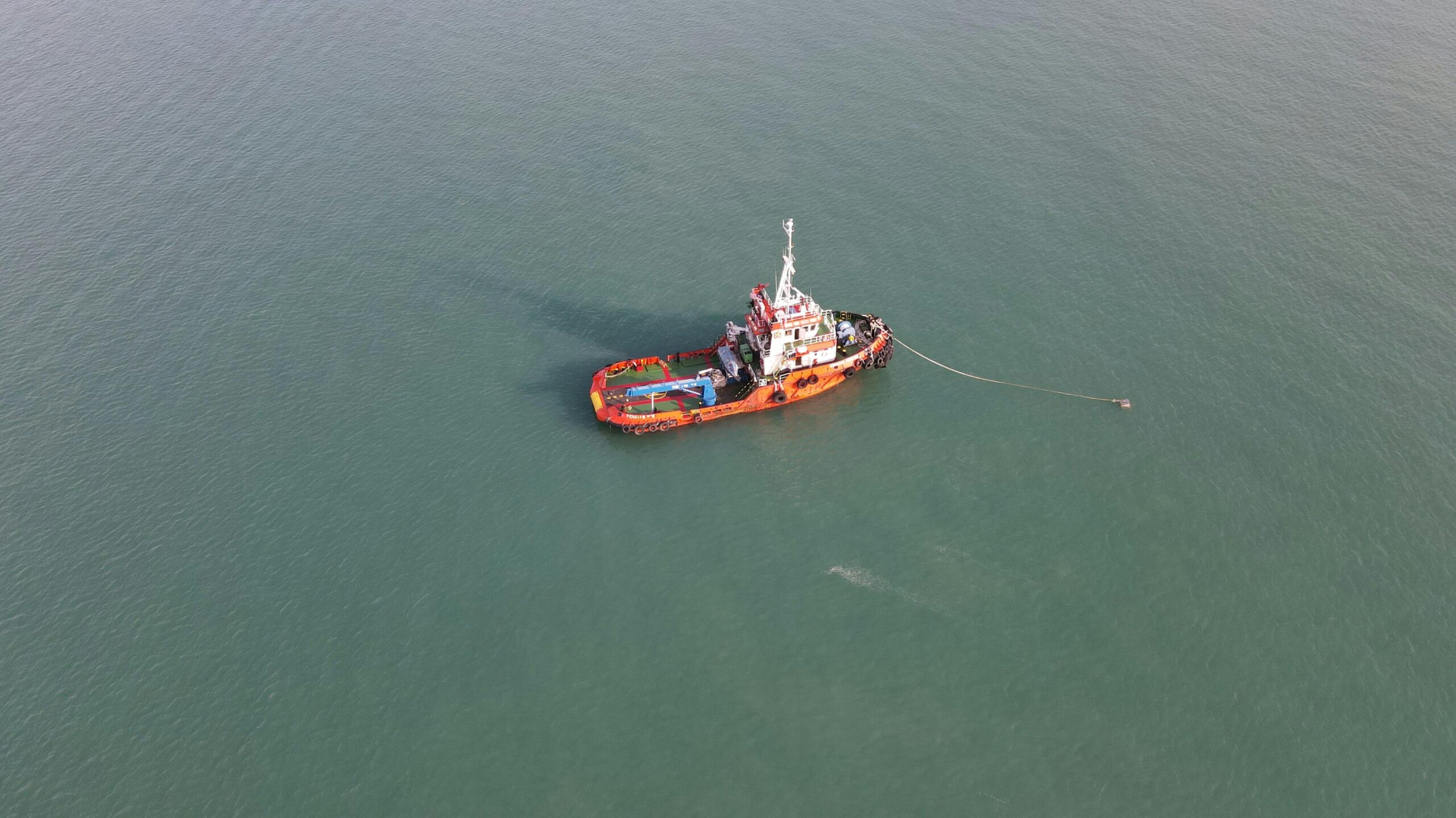 Aerial view of a red tugboat navigating the calm waters in Port Dickson, Malaysia.